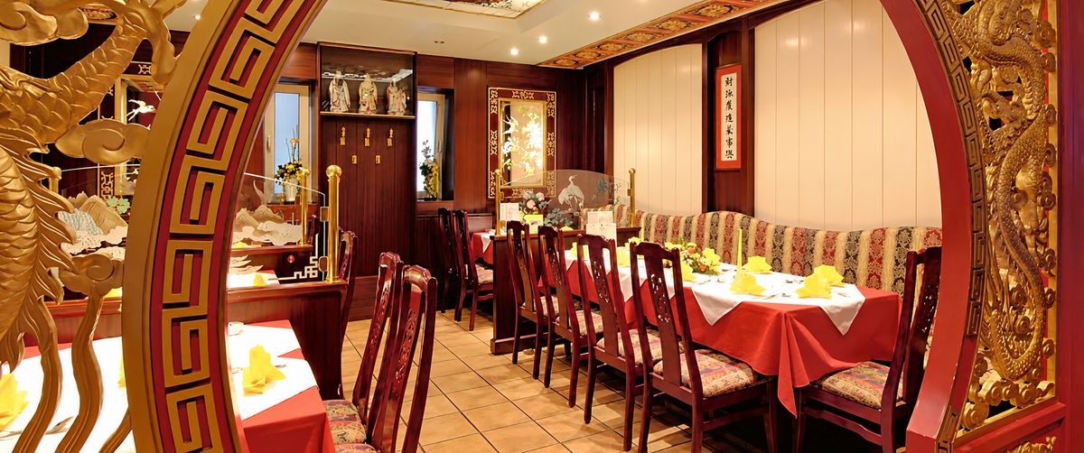 Gastraum des China Restaurants Kink-Lon mit rot gedeckten Tischen und geschnitzten Holzbögen